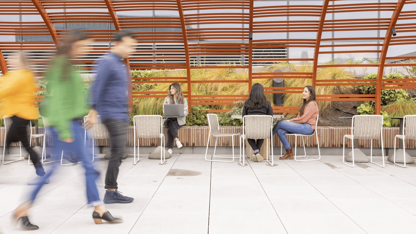 people sitting on chairs in a room with a glass roof