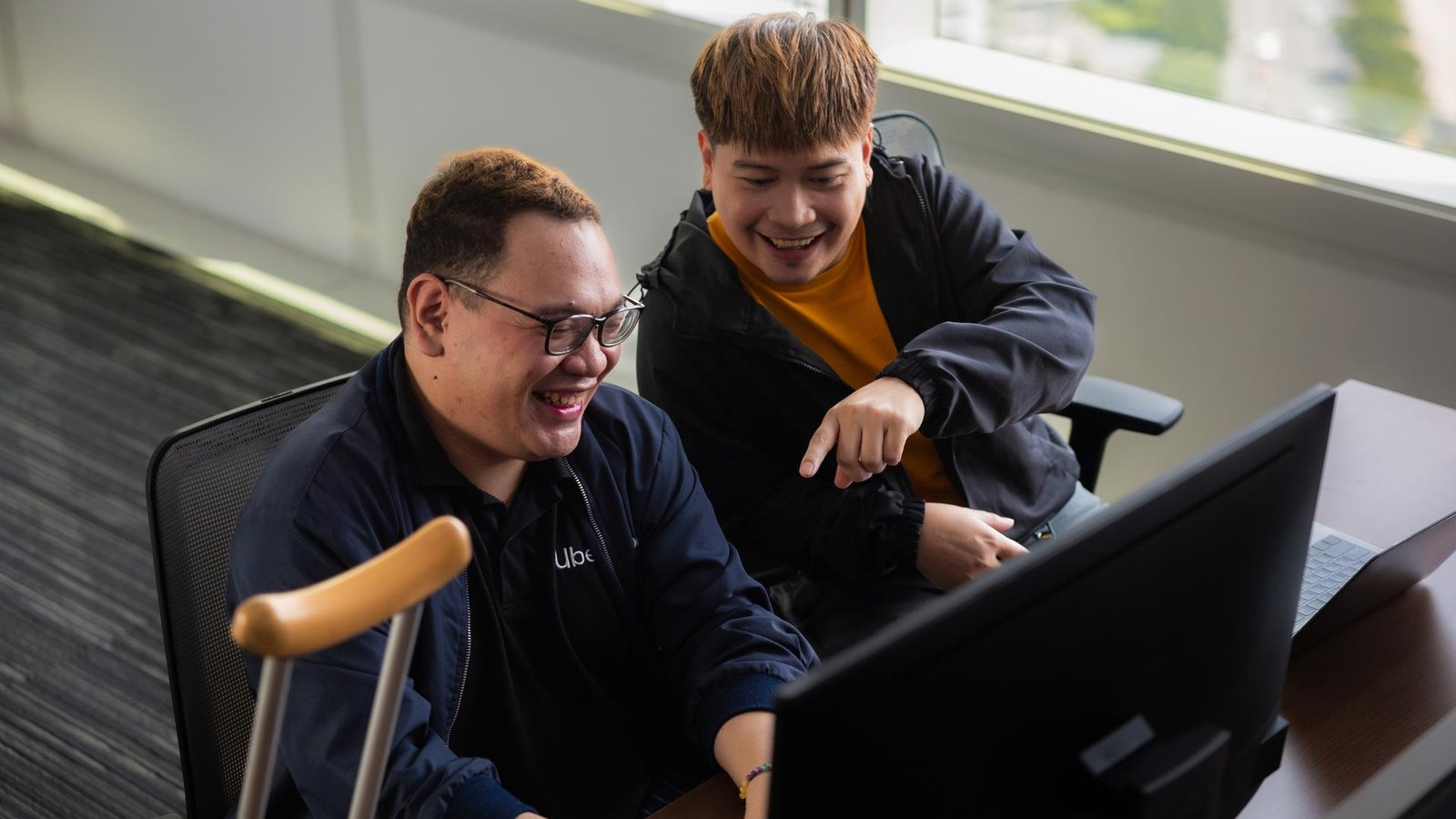 two men laughing at a computer