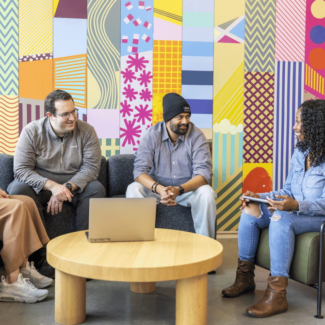 a group of people sitting on couches in front of a colorful wall