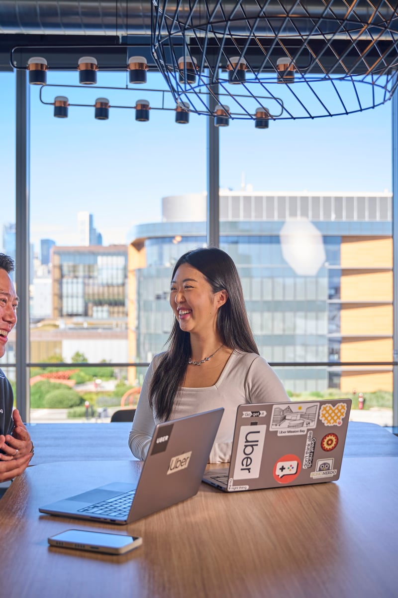 a person and person sitting at a table with laptops