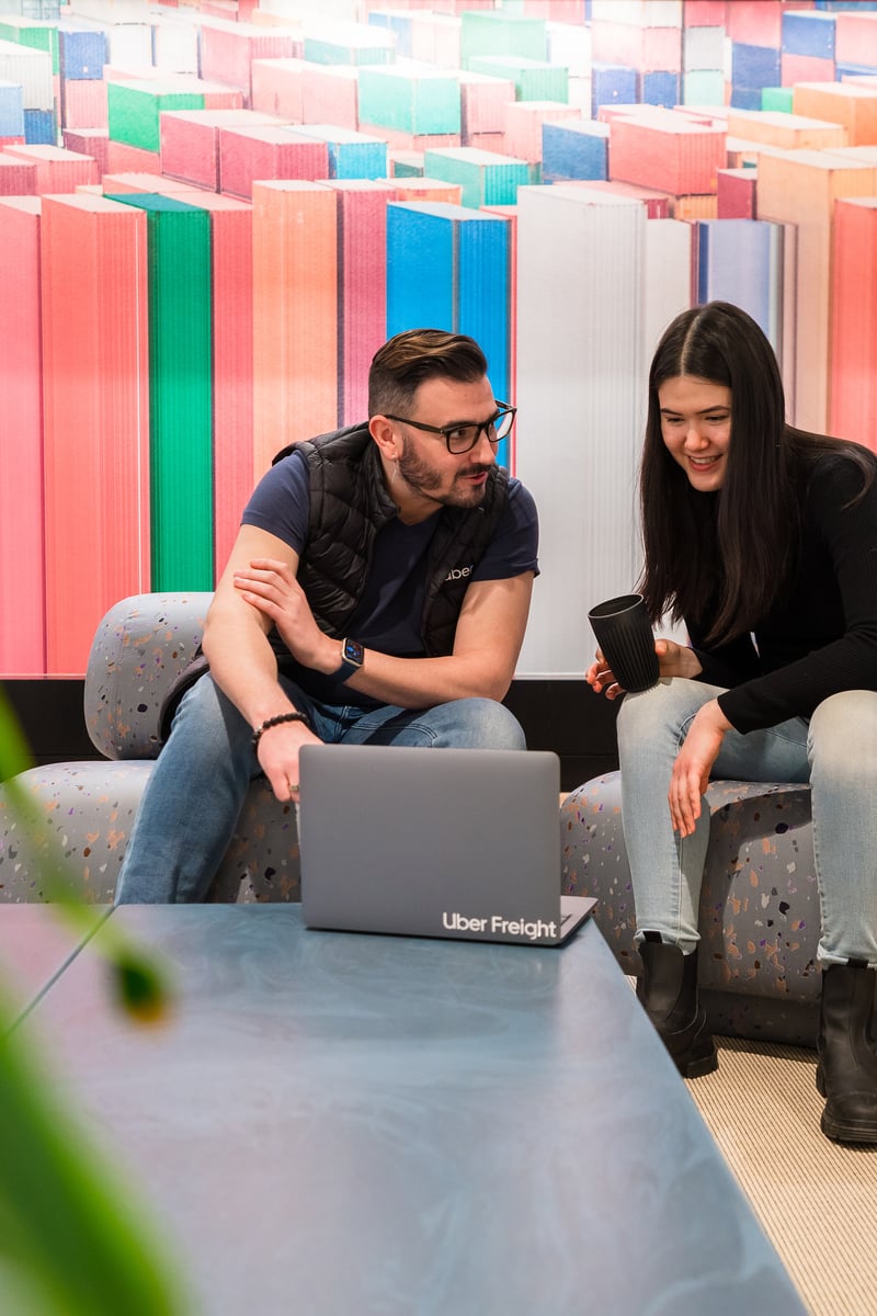 a person and person sitting on couches looking at a laptop