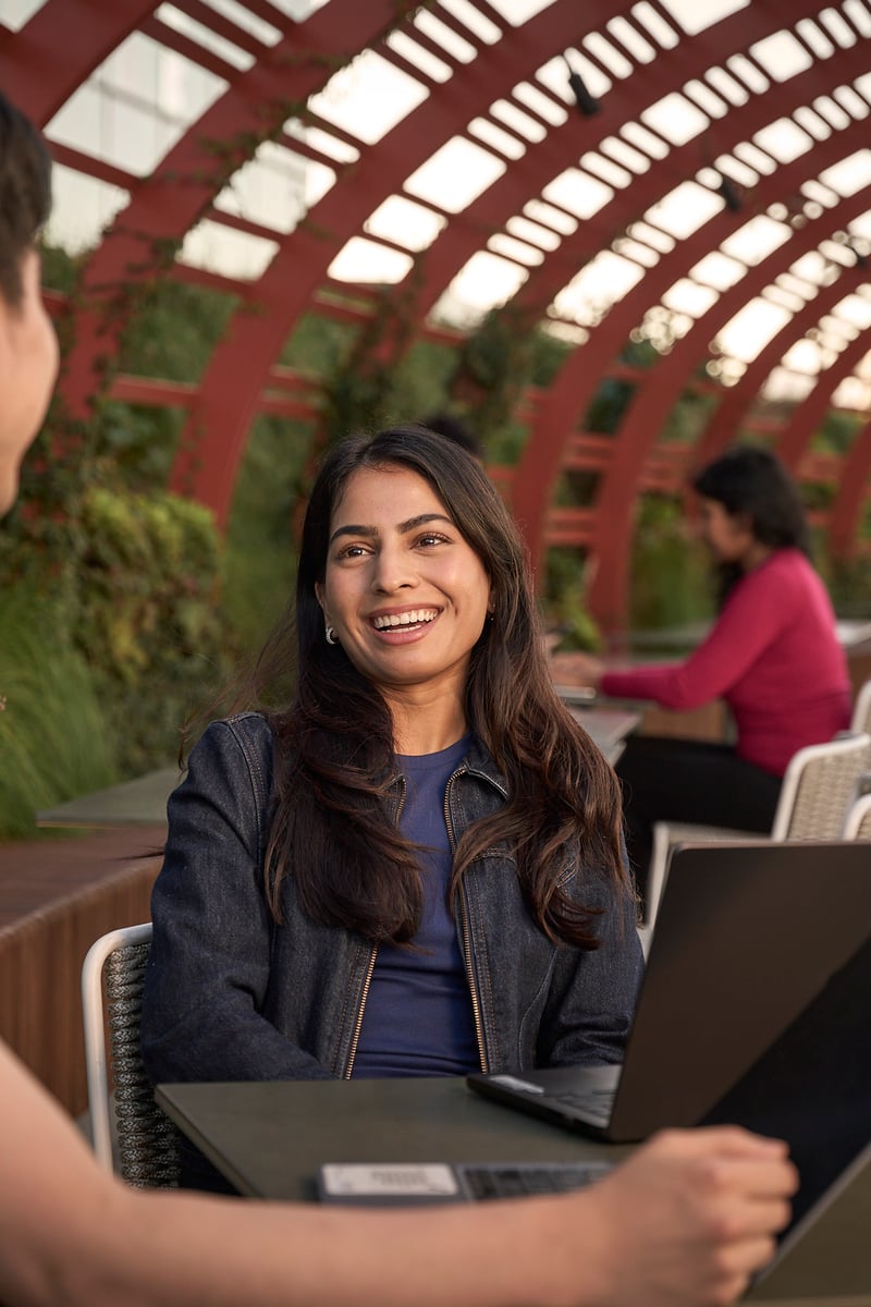 a person and person sitting at a table with a laptop