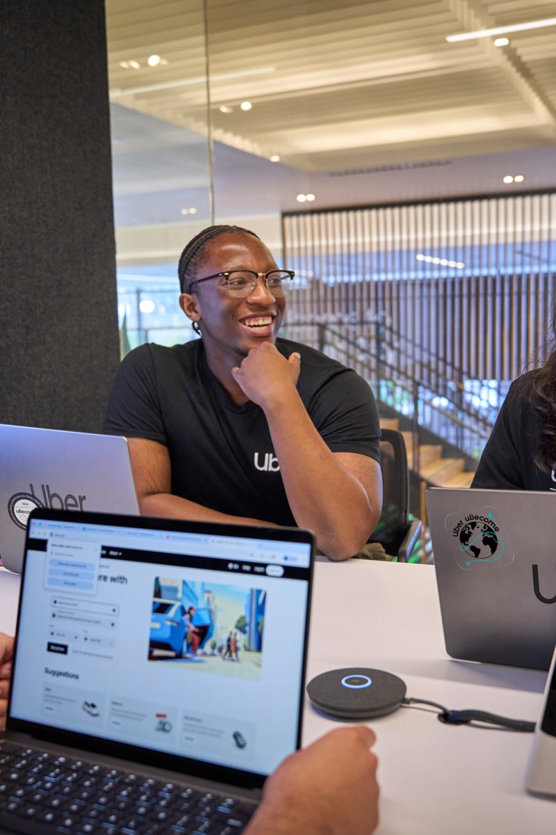 a group of people sitting at a table with laptops