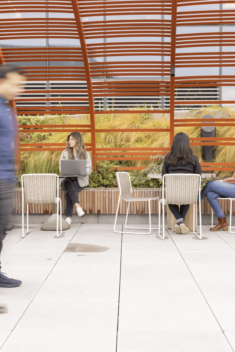 people sitting on chairs in a room with a glass roof