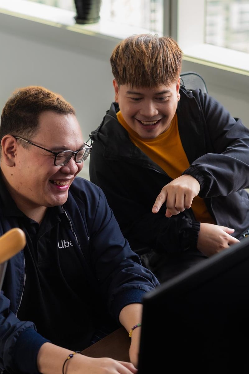 two men laughing at a computer