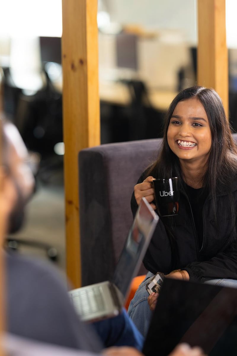 a person holding a cup and smiling while sitting on a couch