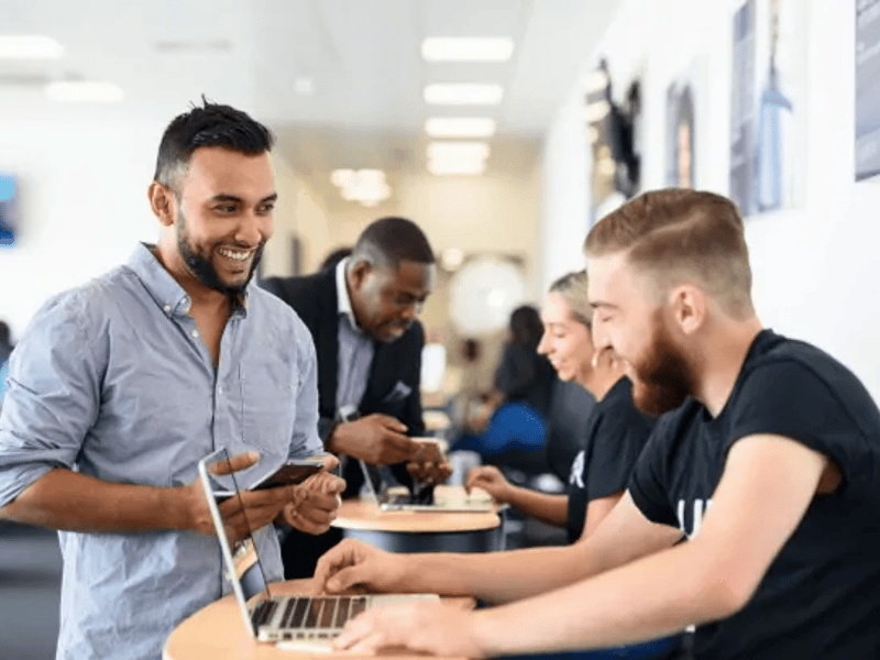 a group of people sitting at tables with laptops
