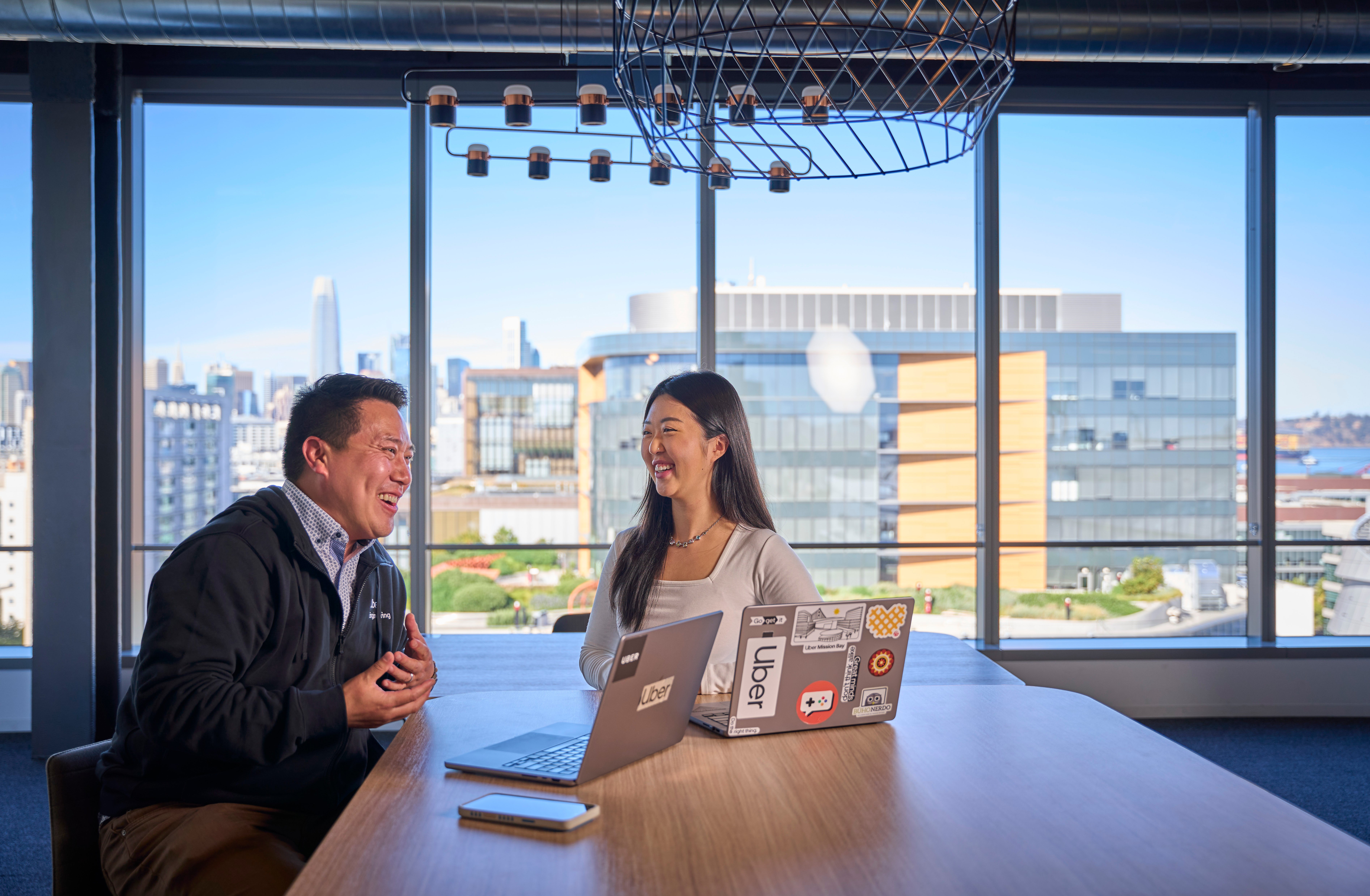 a person and person sitting at a table with laptops
