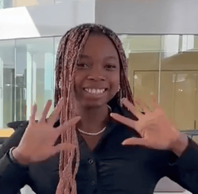 a person with braids holding her hands up