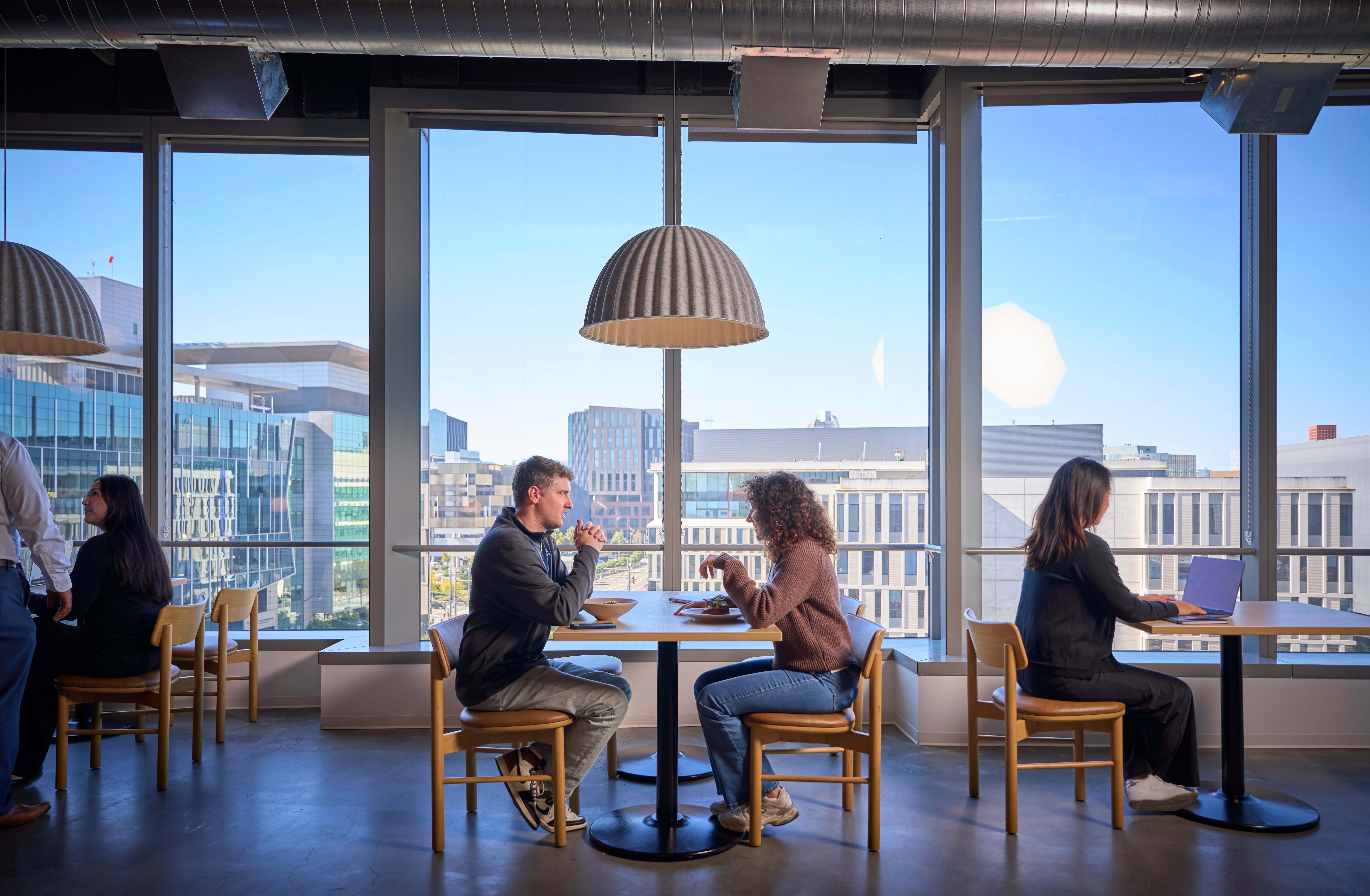 a person and person sitting at a table with a large window
