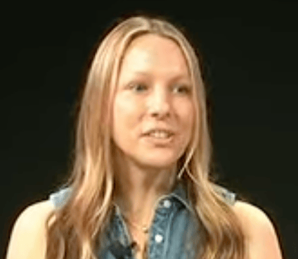 a person with long hair wearing a denim vest